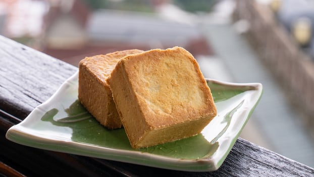 Delicious pineapple pastry in a plate for afternoon tea on wooden railing of a teahouse in Taiwan with beautiful landscape in background, close up. photo