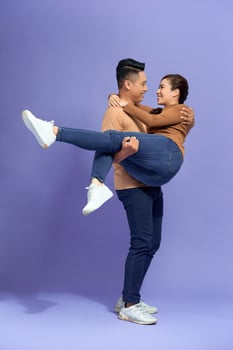 Full length photo of handsome man holding beautiful woman in his arms