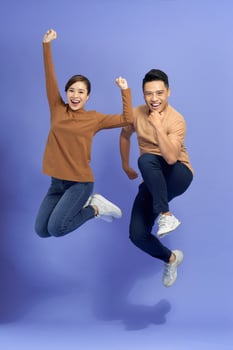 happy smiling couple isolated active jumping on purple background photo