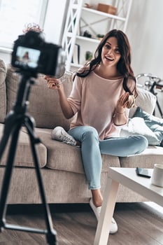 Modern vlogger. Beautiful young woman holding beauty products and smiling while making social media video photo