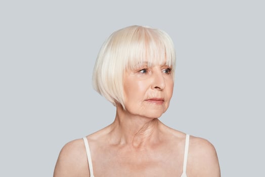 Totally calm. Beautiful senior woman looking away while standing against grey background photo