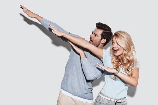 Young and free. Beautiful young couple gesturing and smiling while standing against grey background photo