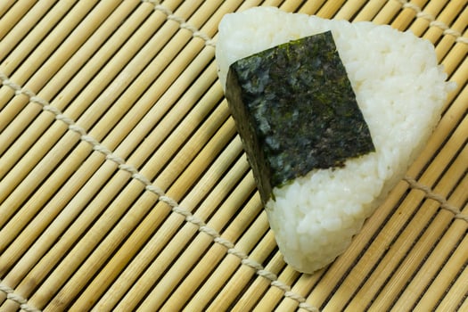 The Japanese food Onigiri  white rice formed into triangular or cylindrical shapes and often wrapped in nori. photo