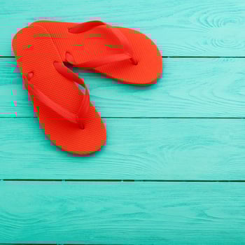 Red flip flops on turquoise wooden background photo