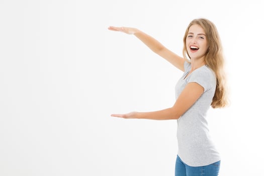 Advertising plase. Portrait of smiling young blonde caucasian woman wearing summer t shirt pointing at copy space by finger isolated on white template and blank background. Shock and excited face. photo