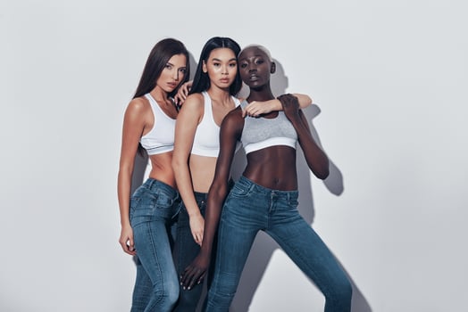 Young and beautiful. Three attractive young women looking at camera while standing against grey background photo