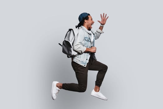 Happy. Handsome young man in casual clothing smiling and gesturing while jumping against grey background photo