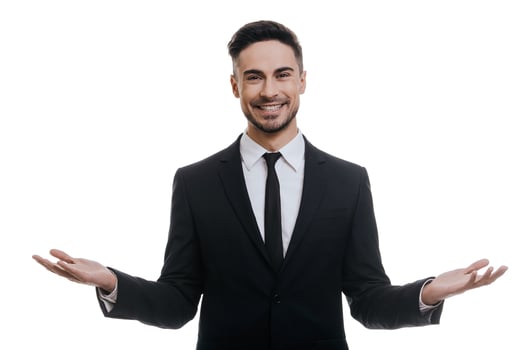 Welcome Handsome young man in full suit looking at camera and keeping arms outstretched while standing against white background photo