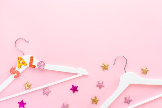 White hangers with sale text on pink background photo