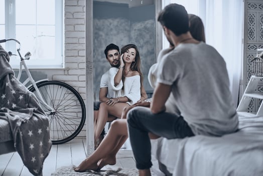Reflection of true love. Rear view of beautiful young couple looking in the mirror on their reflection while sitting on the bed at home photo