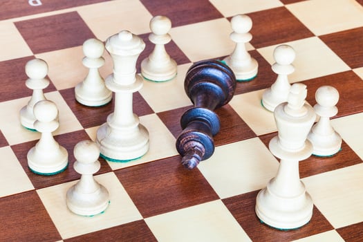black chess king surrounded by white pieces photo