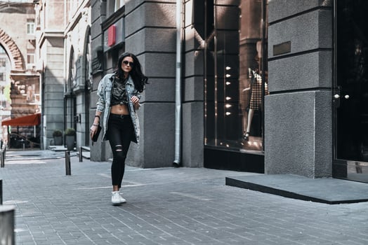 City girl. Full length of young attractive woman in denim jacket walking while spending time outdoors photo