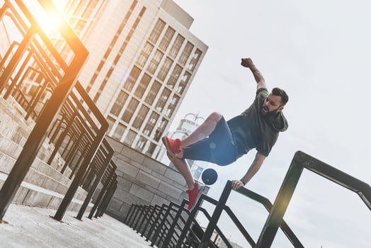 Ready to overcome any obstacle. Full length of handsome young man in sport clothing jumping over railing while exercising outside photo
