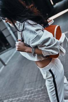 Cool outfit. Young beautiful woman in sport wear carrying a backpack while walking outdoors photo