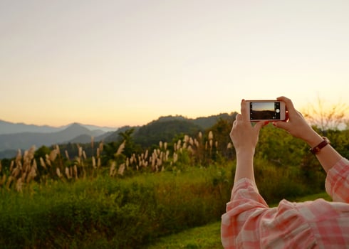 Young asian woman taking a photo with her phone in beautiful mountain view