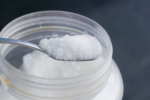 white sugar and spoon in a container on black background, photo