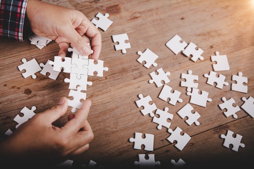Hands holding jigsaw puzzles piece on wooden table background, success business, solution strategy, teamwork partnership concept photo