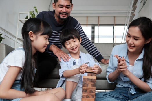 Happy Asian lovely Thai family activity, parents, dad, mum, and children have fun playing and joyful wooden toy blocks together on living room floor, leisure weekend, and domestic wellbeing lifestyle. photo