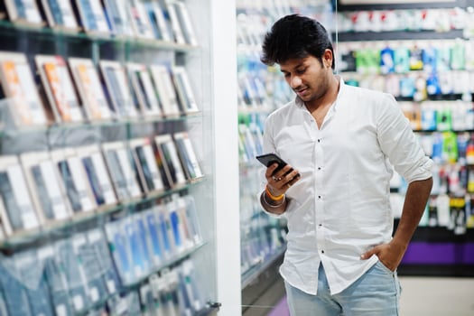 Indian man customer buyer at mobile phone store choose his new smartphone. South asian peoples and technologies concept. Cellphone shop. photo