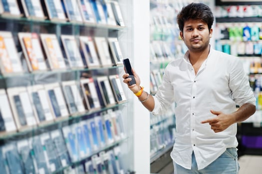 Indian man customer buyer at mobile phone store choose his new smartphone. South asian peoples and technologies concept. Cellphone shop. photo