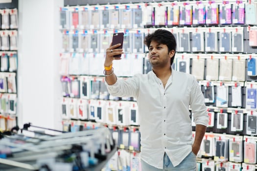 Indian man customer buyer at mobile phone store making selfie on his new smartphone with case. South asian peoples and technologies concept. Cellphone shop. photo