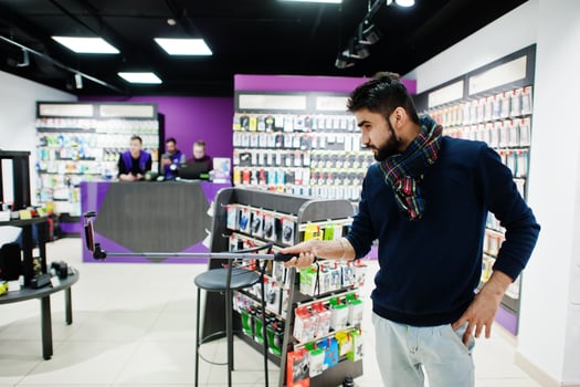 Indian man customer buyer at mobile phone store making selfie by smartphone on monopod stick. South asian peoples and technologies concept. Cellphone shop. photo
