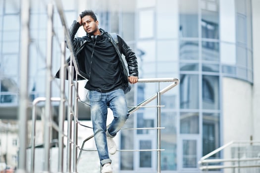 Stylish and casual asian man in black leather jacket posed near the railing against modern building. photo