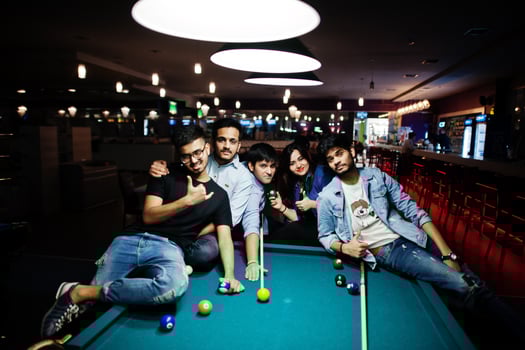 Group of stylish asian friends wear on jeans playing pool billiard on bar. photo