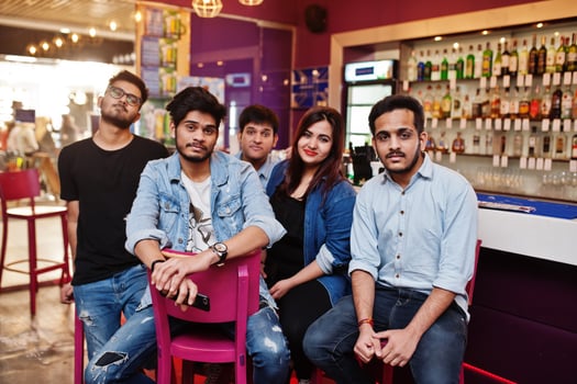 Group of stylish asian friends wear on jeans sitting at chairs against bar in club. photo