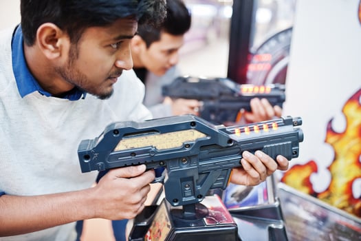 Two asian guys compete on shooter simulator game arcade machine. photo