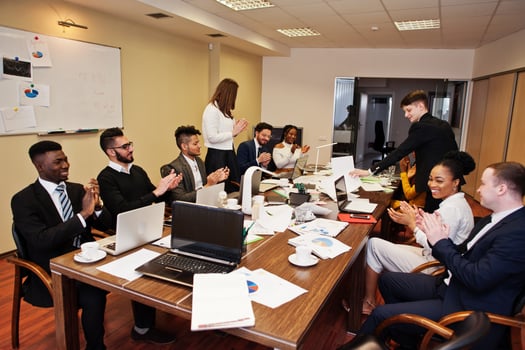 Multiracial business team meeting around boardroom table, clap hands. photo