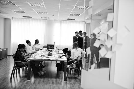 Multiracial business team addressing meeting around boardroom table and write plan on board. photo