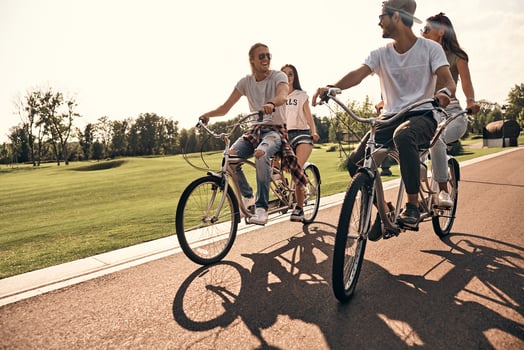 Best day ever. Group of happy young people in casual wear smiling while cycling together outdoors photo