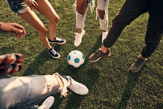 Close-up of young people in casual wear playing soccer while spending time outdoors photo