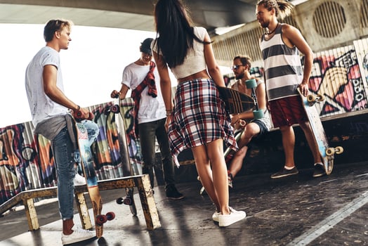 Young and full of energy. Group of young modern people in casual wear talking while spending time at the skateboard park outdoors photo