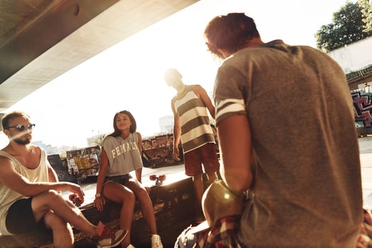 Simply being around. Group of skater friends hanging out together while resting under the bridge outdoors photo