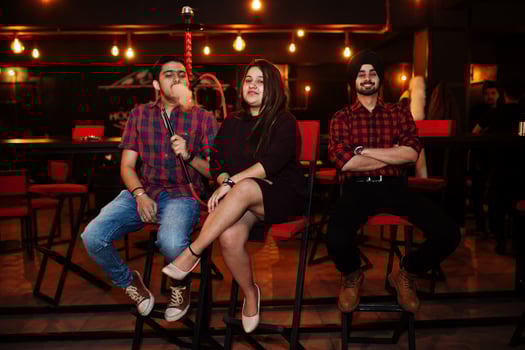 Group of indian friends sitting at lounge bar, smoke hookah and having rest. photo