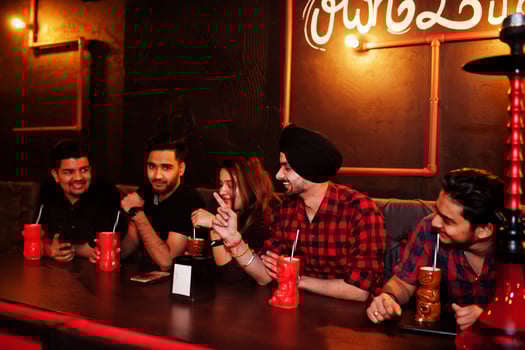Group of indian friends having fun and rest at night club, drinking cocktails and smoke hookah. photo
