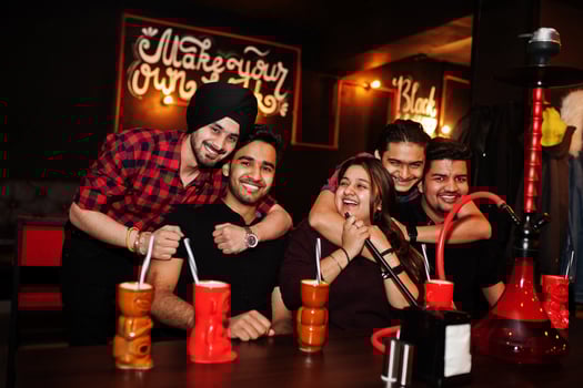 Group of indian friends having fun and rest at night club, drinking cocktails and smoke hookah. photo