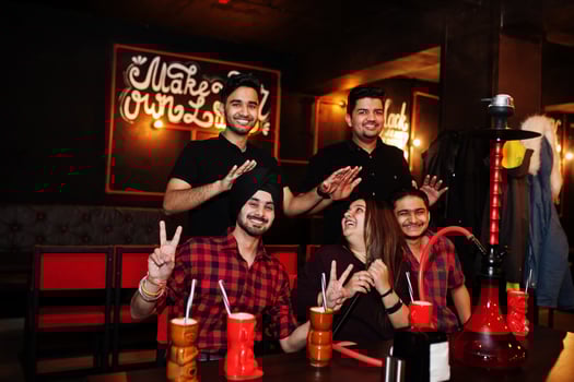 Group of indian friends having fun and rest at night club, drinking cocktails and smoke hookah. Blessed friendship. photo