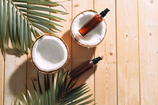 Tropical leaf, care cosmetics and coconut on a wooden table. Top view. Means for hair, body, skin. flatlay photo