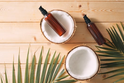 Tropical leaf, care cosmetics and coconut on a wooden table. Top view. Means for hair, body, skin. flatlay photo