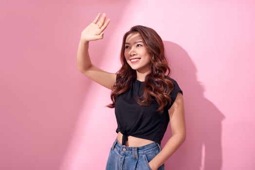 Portrait of an attractive young woman raising her hand to shade her face from the sun rays during a sunny day smiling photo