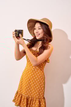 Image of young photographer woman isolated over beige background wall holding camera. photo