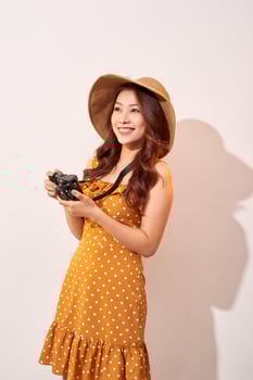 Image of young photographer woman isolated over beige background wall holding camera. photo