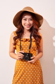 Image of young photographer woman isolated over beige background wall holding camera. photo