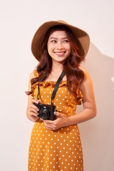 Image of young photographer woman isolated over beige background wall holding camera. photo