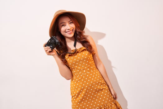 Image of young photographer woman isolated over beige background wall holding camera. photo