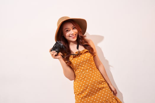 Image of young photographer woman isolated over beige background wall holding camera. photo