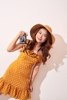 Image of young photographer woman isolated over beige background wall holding camera. photo